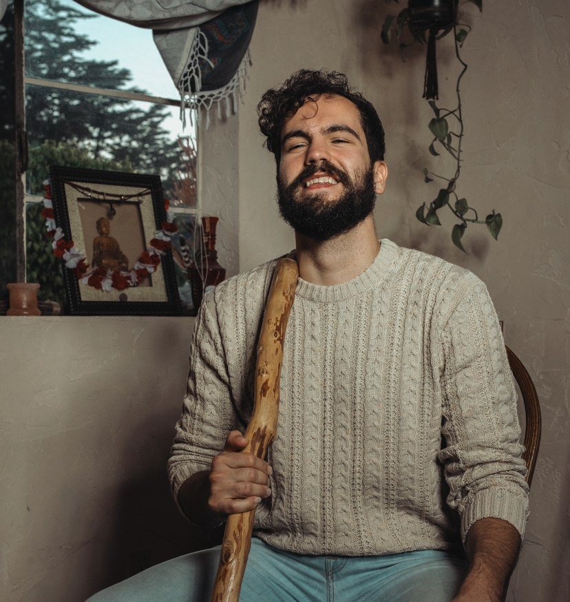 Alex Van Valen, life coach, smiling and holding a carved wooden staff