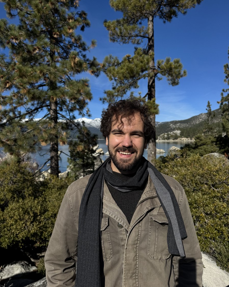 Alex Van Valen outdoors among pines above a mountain lake
